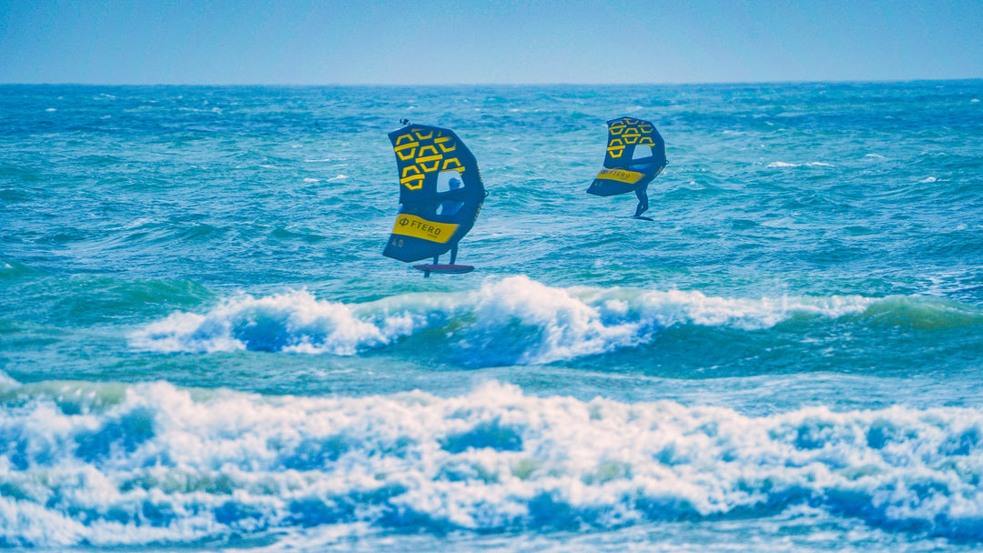 two wingfoilers wingfoiling in the sea