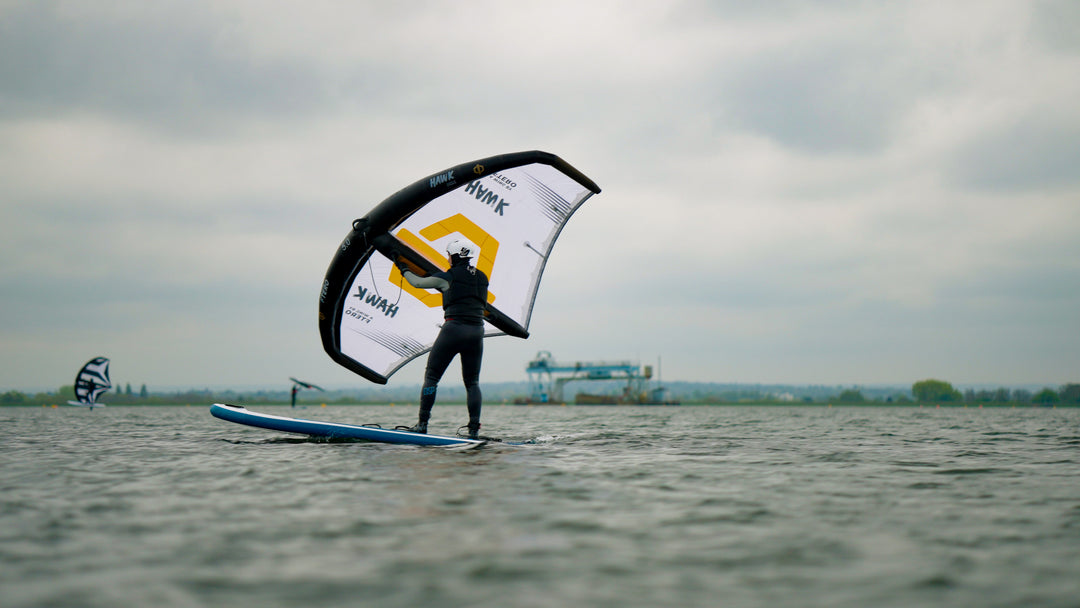 beginner learning how to wingfoil on a stand up paddleboard SUP